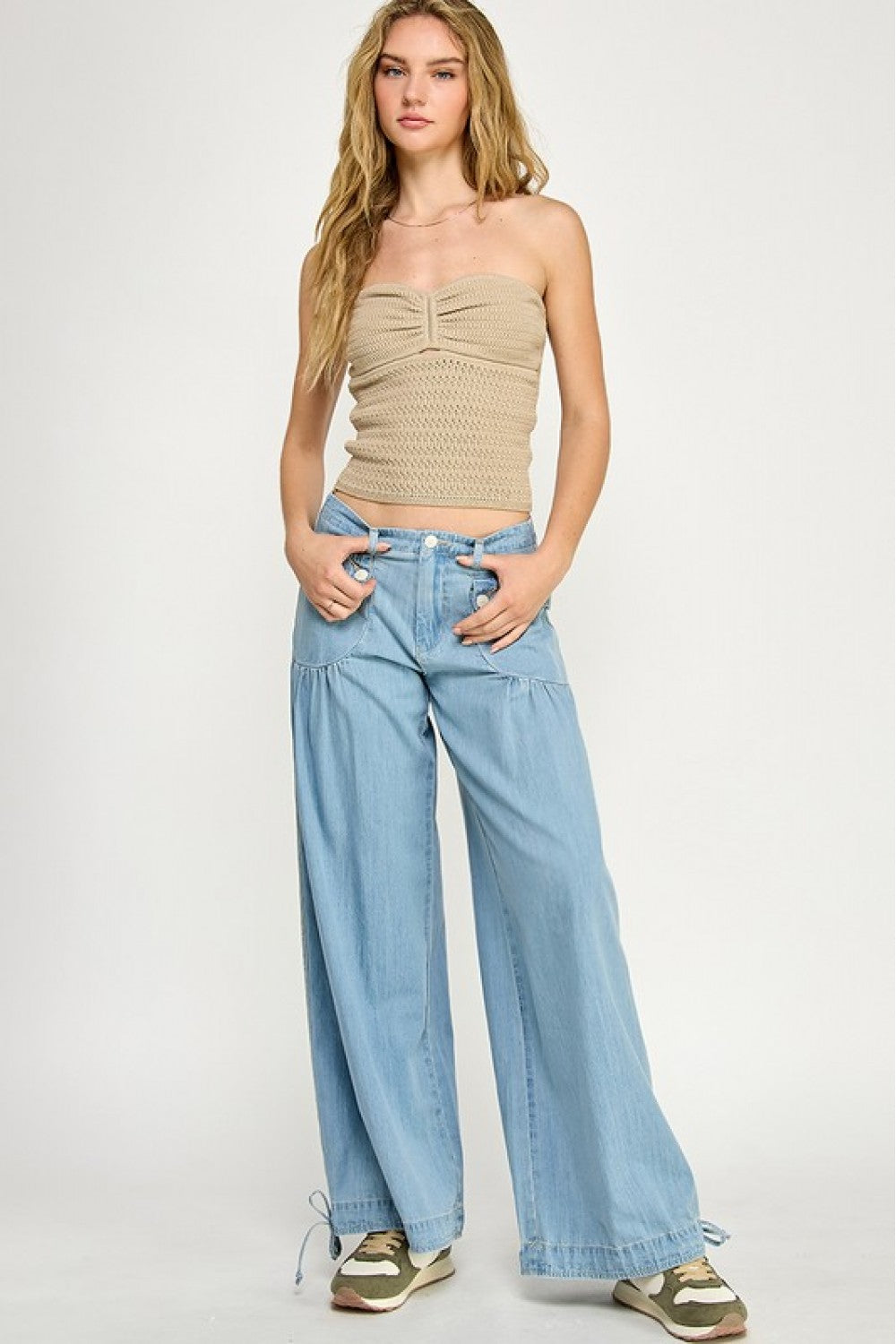 Beige crochet bandeau top with ruched center and keyhole detail, styled with light-wash denim pants.