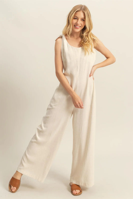 Beige linen-blend wide-leg jumpsuit with tie shoulder straps.